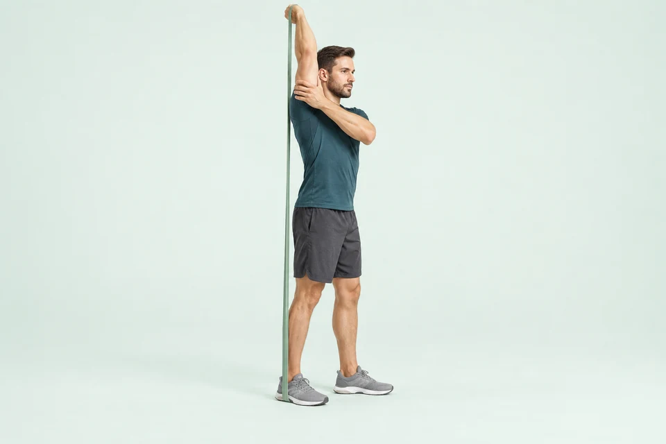 Single-arm overhead triceps extension with band anchored under the same-side foot and passing behind the torso.