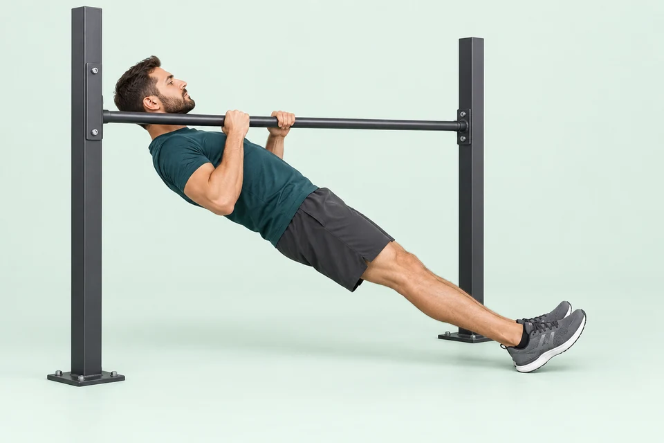 Inverted row beneath a secured low bar with grounded heels, straight body and chest close to the bar.